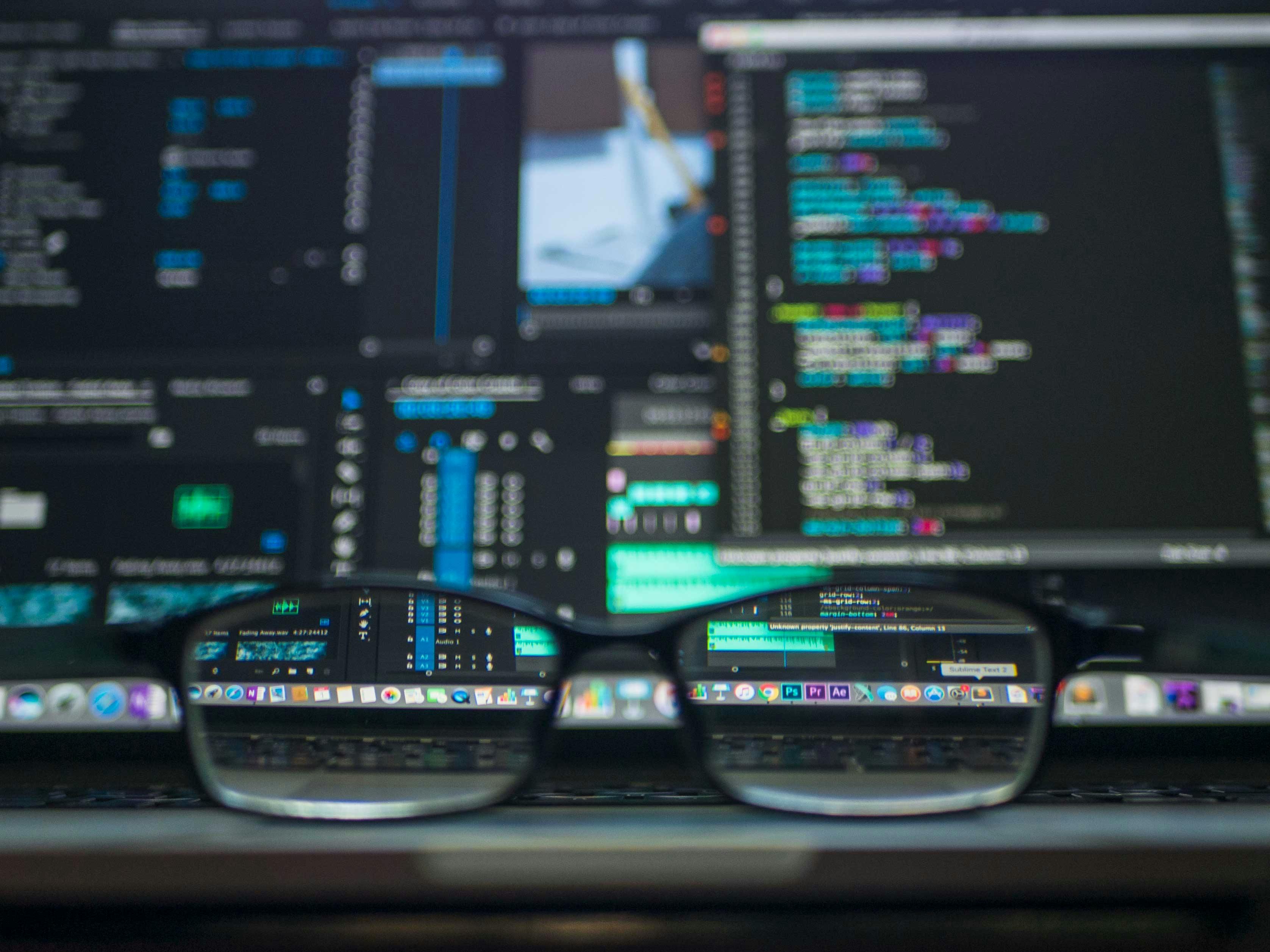 Glasses in front of a computer screen, which is showing some code.